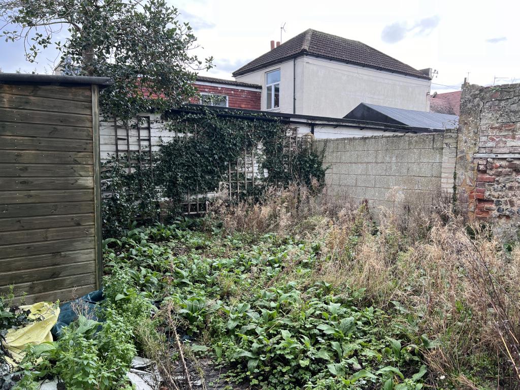 Lot: 23 - SIX-BEDROOM GUEST HOUSE - Rear garden with some overgrowth and storage shed